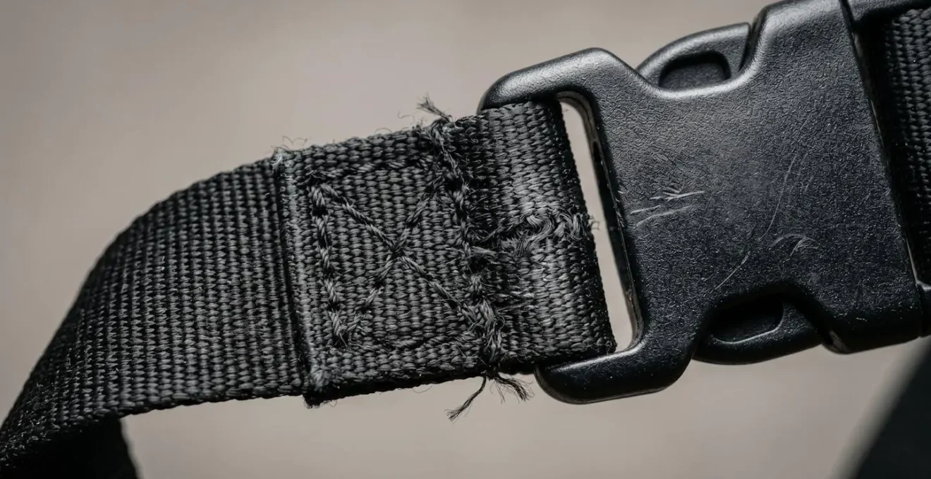 Gros plan détaillé sur les coutures et points de rupture d'un harnais de promenade en nylon sous tension